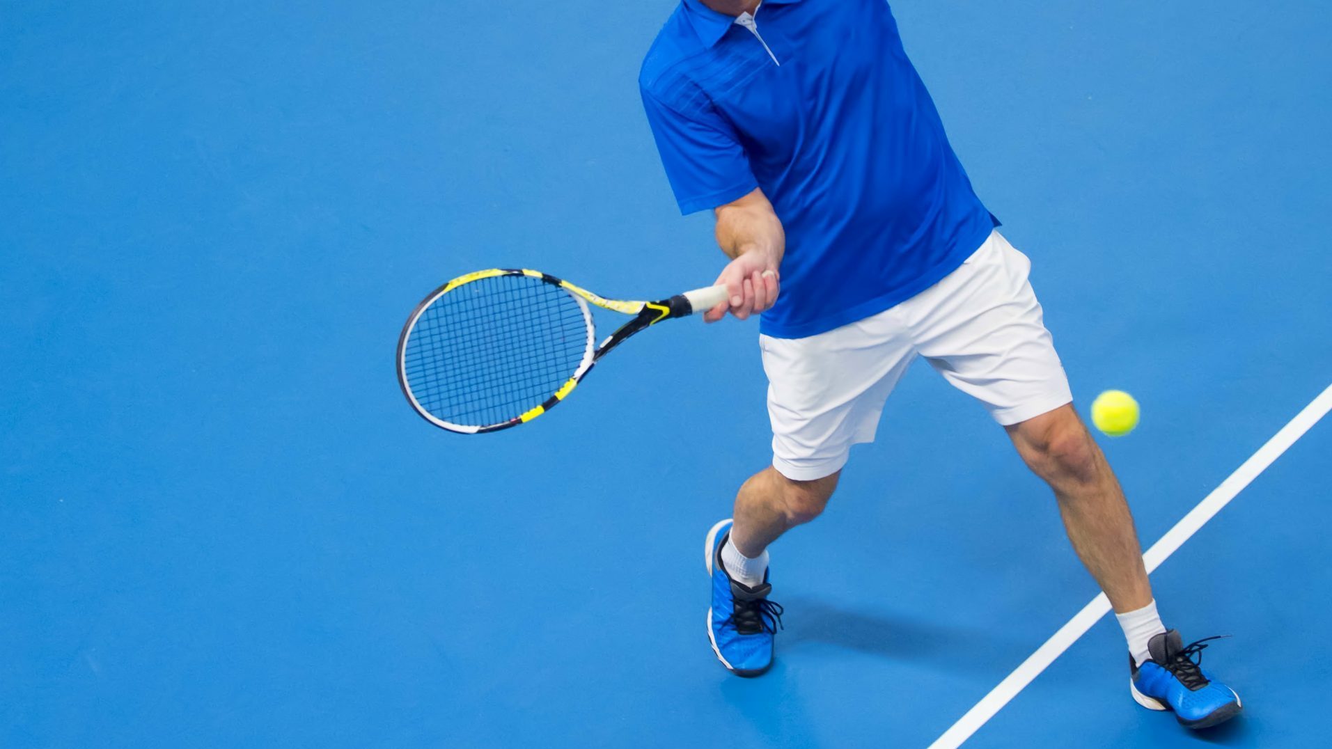 man playing tennis on blue floor